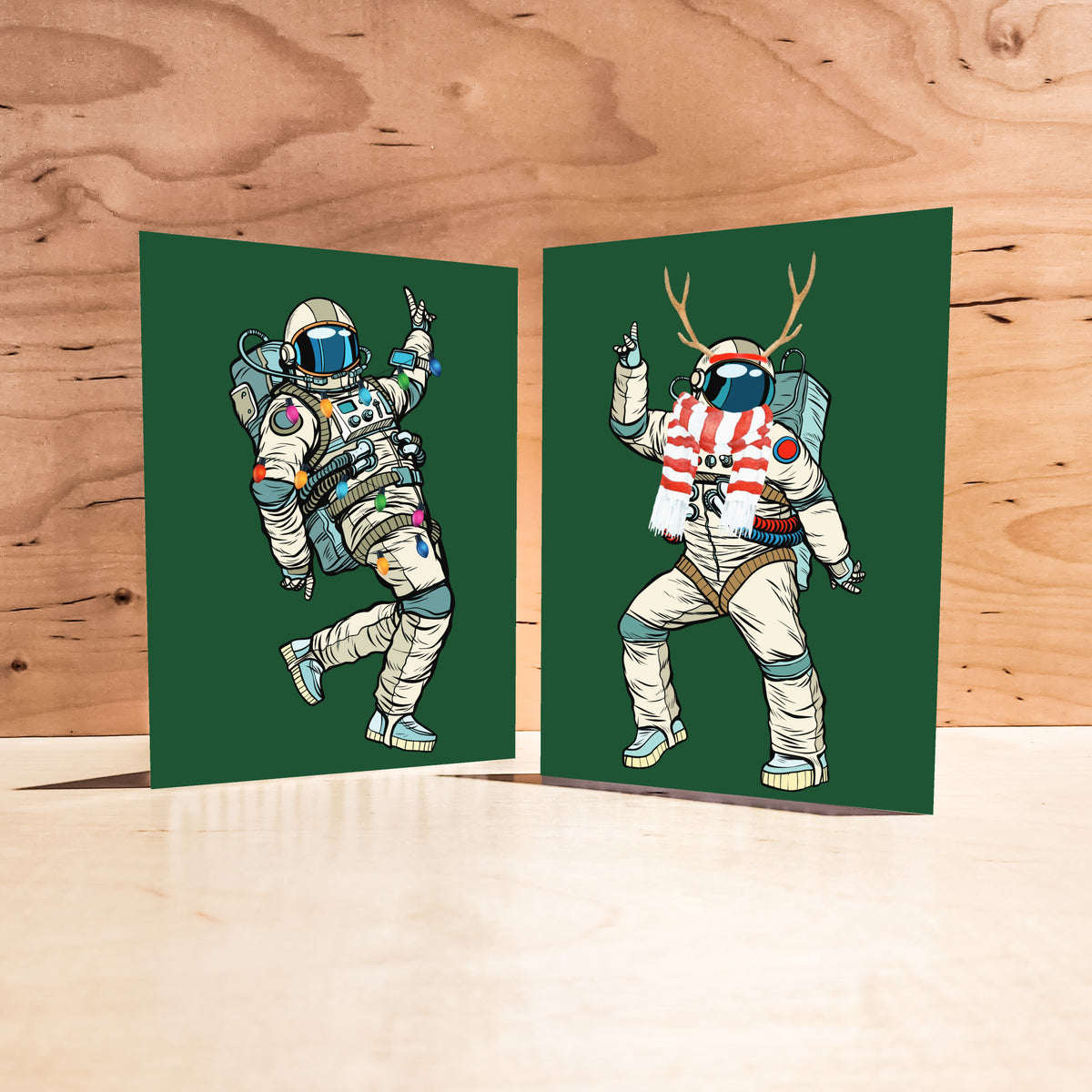Line-art astronaut wearing colorful holiday lights wrapped around spacesuit on dark green card.