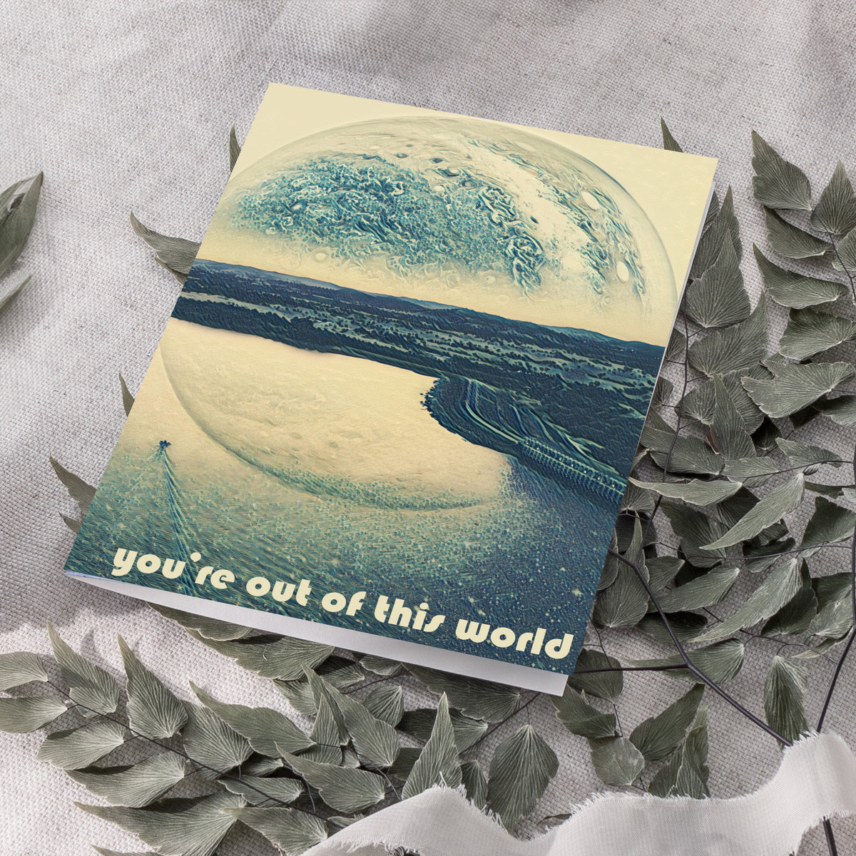 Card featuring the phrase "you're out of this world" in small rounded cream lettering against a surrealistic landscape.