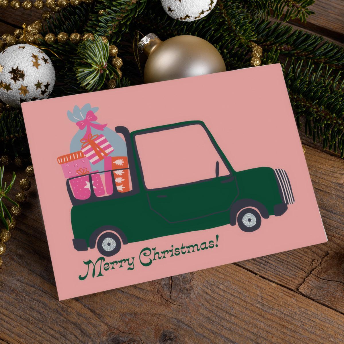 Christmas cards in landscape format with blush pink backgrounds and colorful illustrated vehicles.