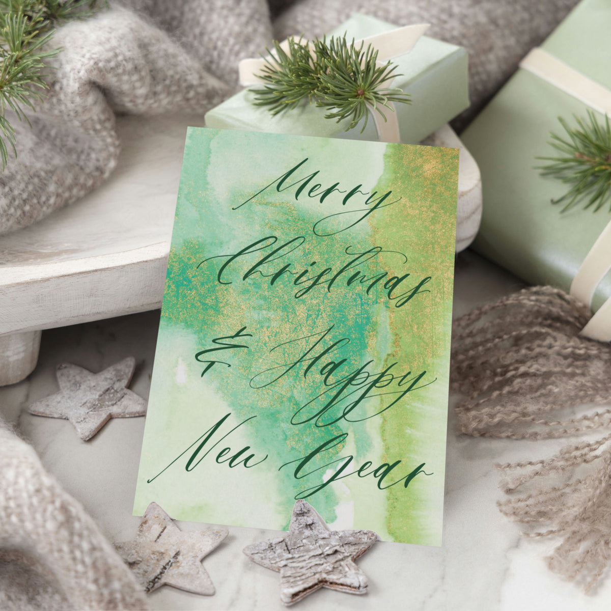 Folded note cards with matching envelopes, holiday script greetings in green and teal on watercolor backgrounds.