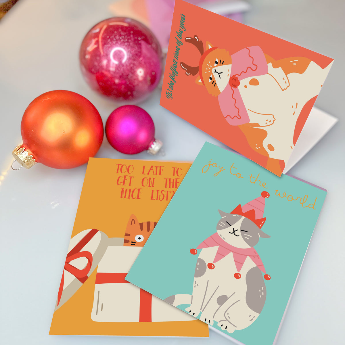Holiday card set depicting cats tangled in lights, toppling trees, and peeking from gift boxes.