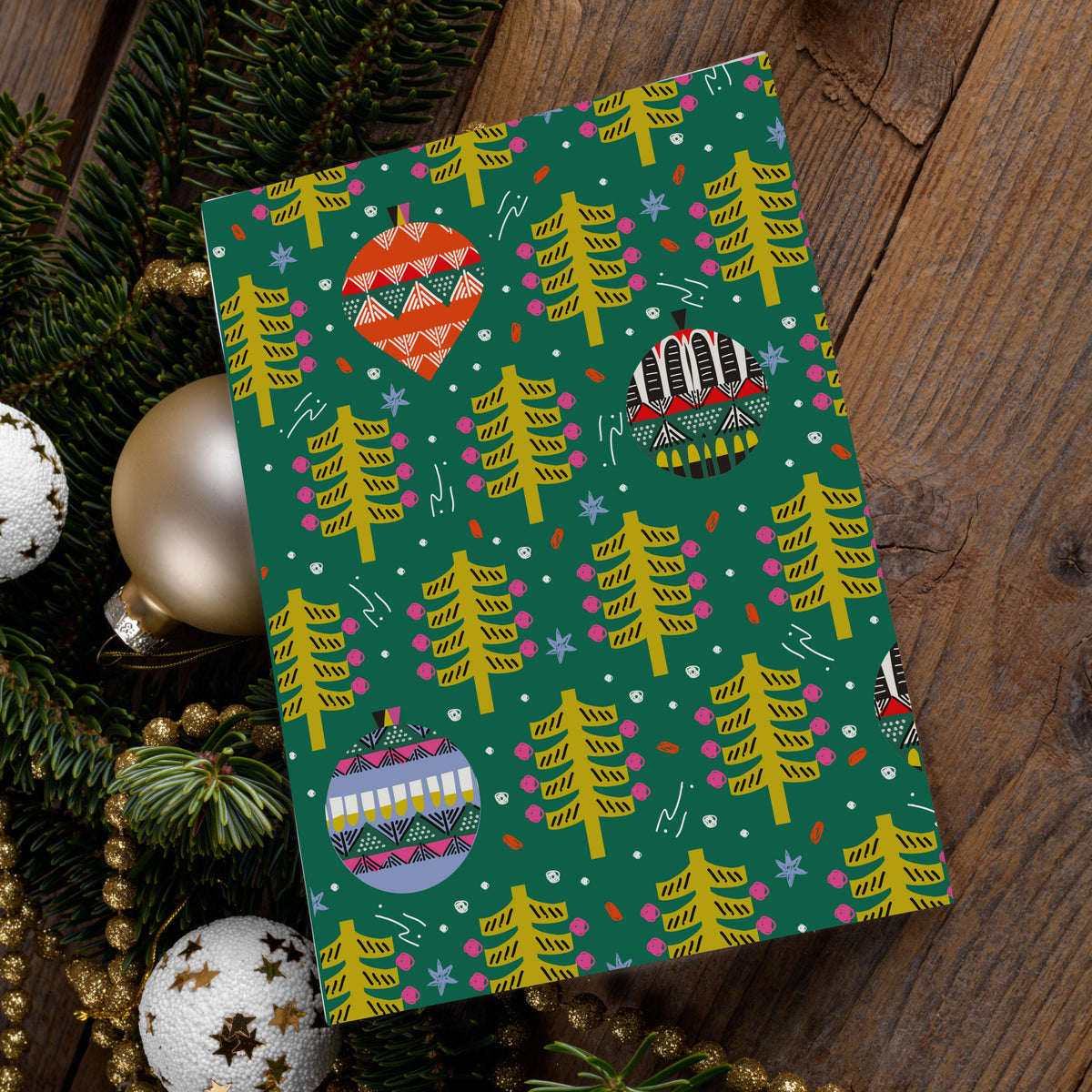 Pink card with white script reading Merry Christmas, surrounded by ornaments, swirls, and dots.