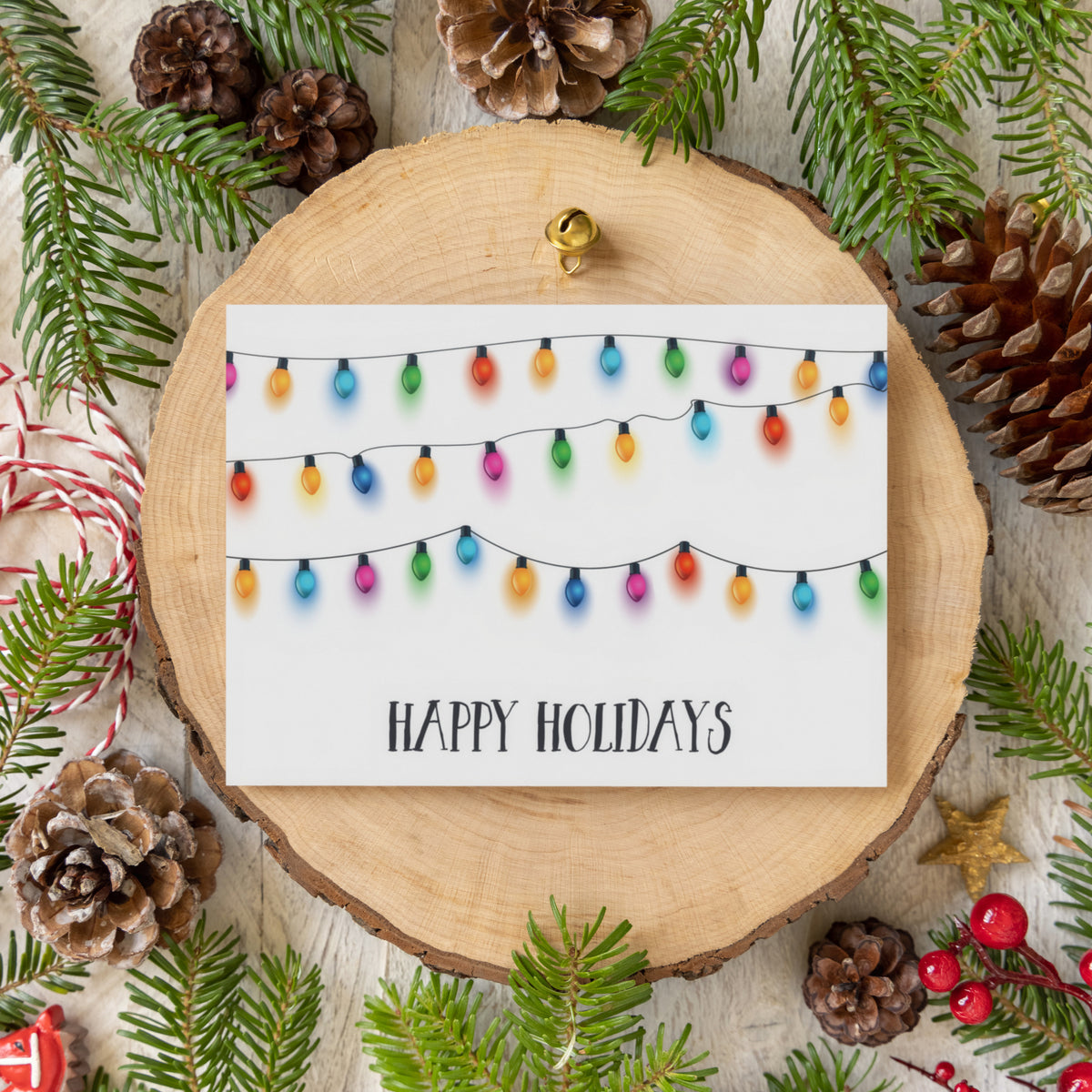 Three rows of mixed-color string light bulbs fill the upper portion of a white holiday card.