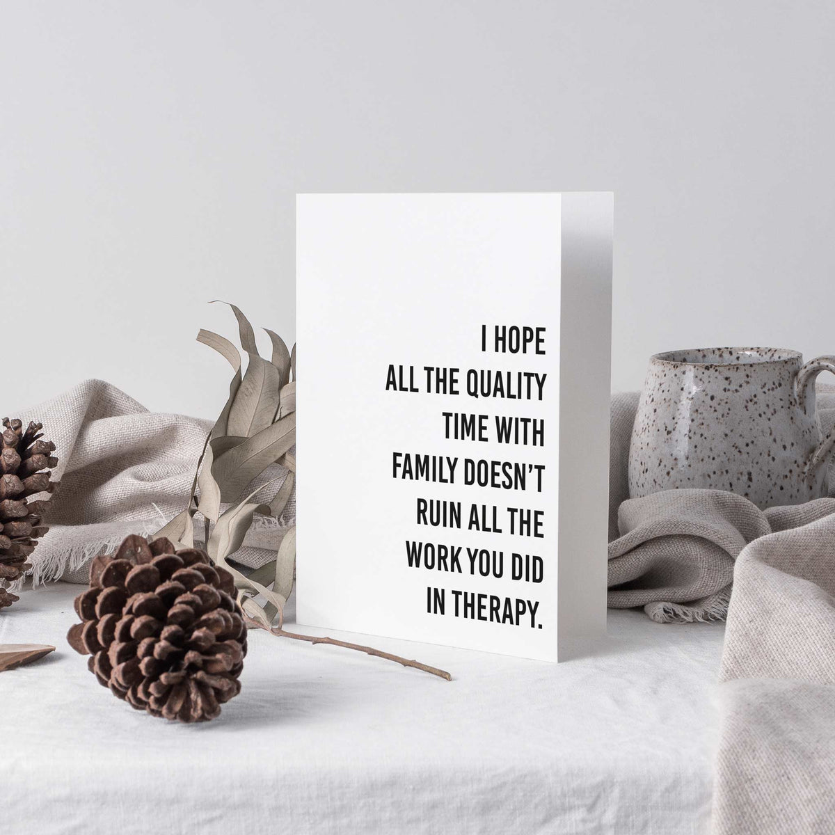 Folded holiday cards in 12 designs, black condensed sans-serif phrases on white card stock.
