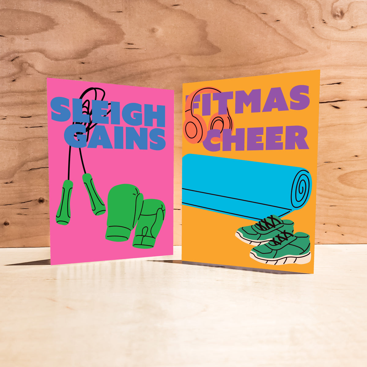 Flat-color fitness Christmas card set, six pun designs on bright backgrounds with display lettering and gym equipment illustr