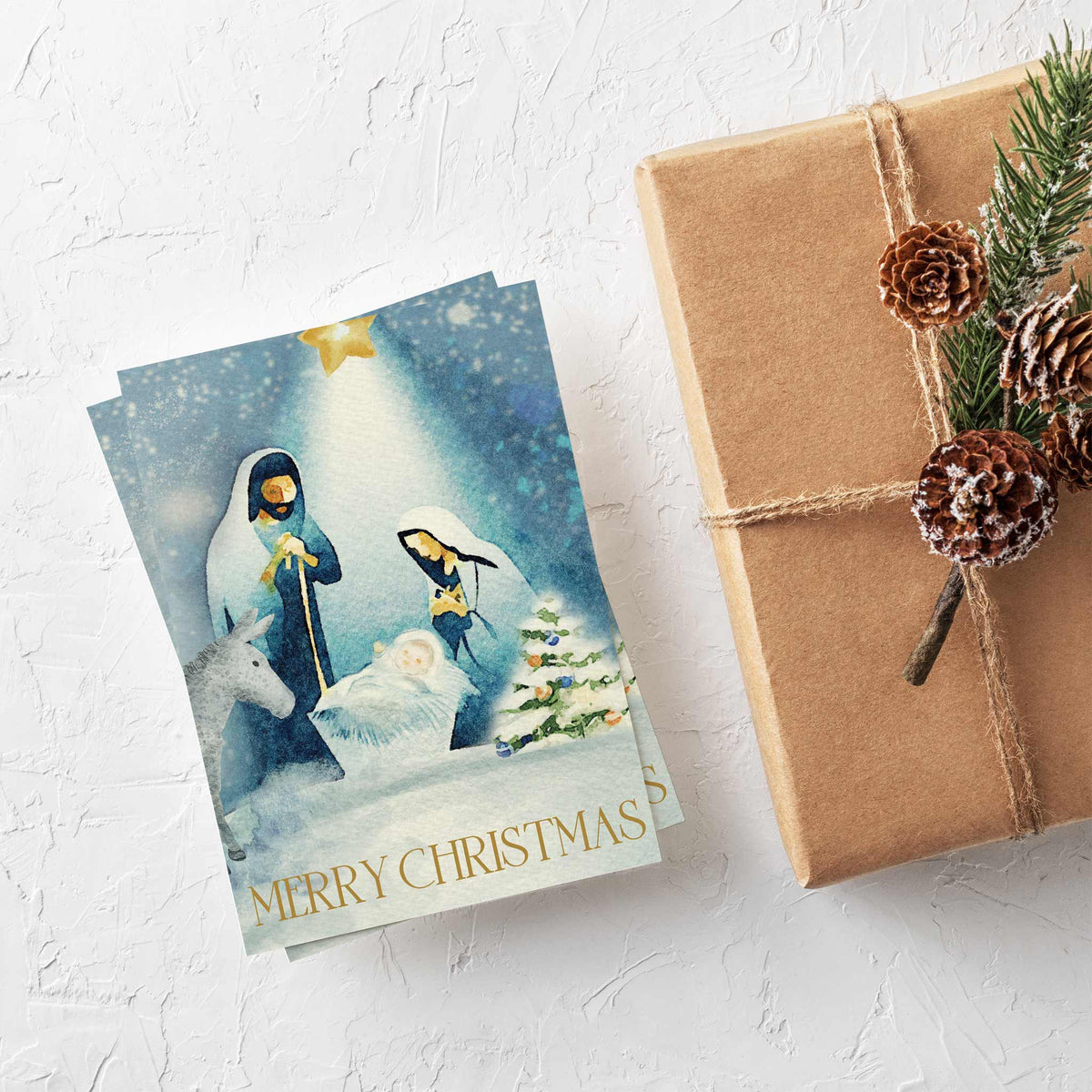 Box of 24 matching Christmas cards with deep blue watercolor nativity illustration and gold star with radiating light.