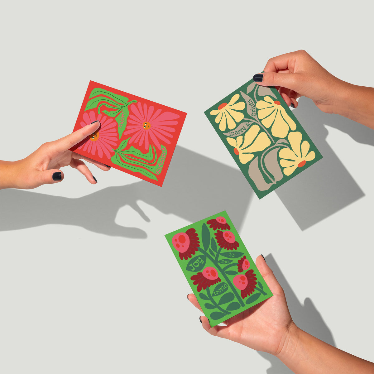 Christmas cards with bold botanical illustrations and full-bleed solid backgrounds in holiday colors.