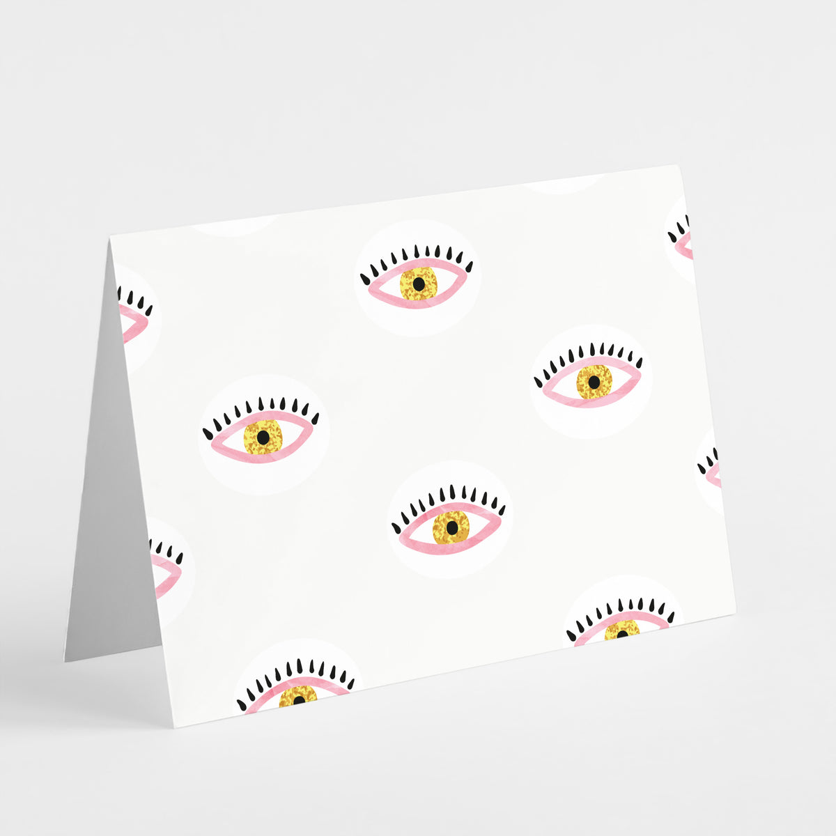 Graphic notecard set of 24 cards with repeating eye pattern designs in pink, white, yellow, and black.