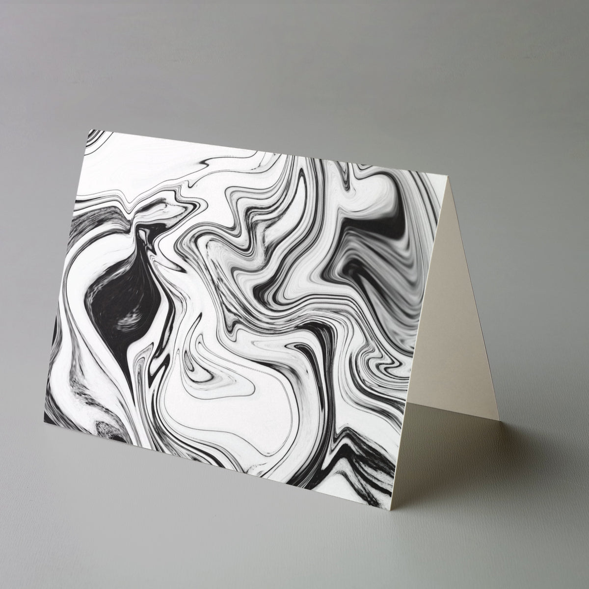 Two fluid marbled designs on landscape note cards, one dark-dominant and one predominantly white.