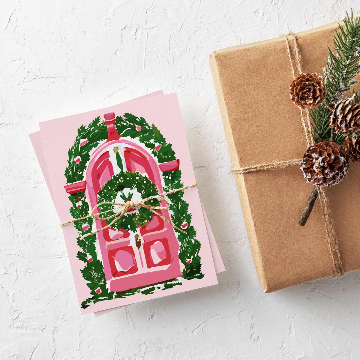 Set of 24 Christmas cards, four designs rotating six cards each, pink doors with garland and wreath illustrations.