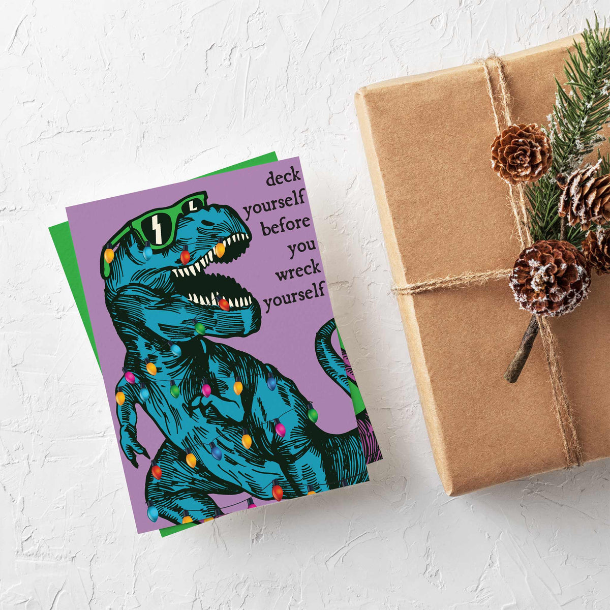 Engraving-style T-rex in sunglasses with bulbs in its open mouth, Christmas card, two background colors.