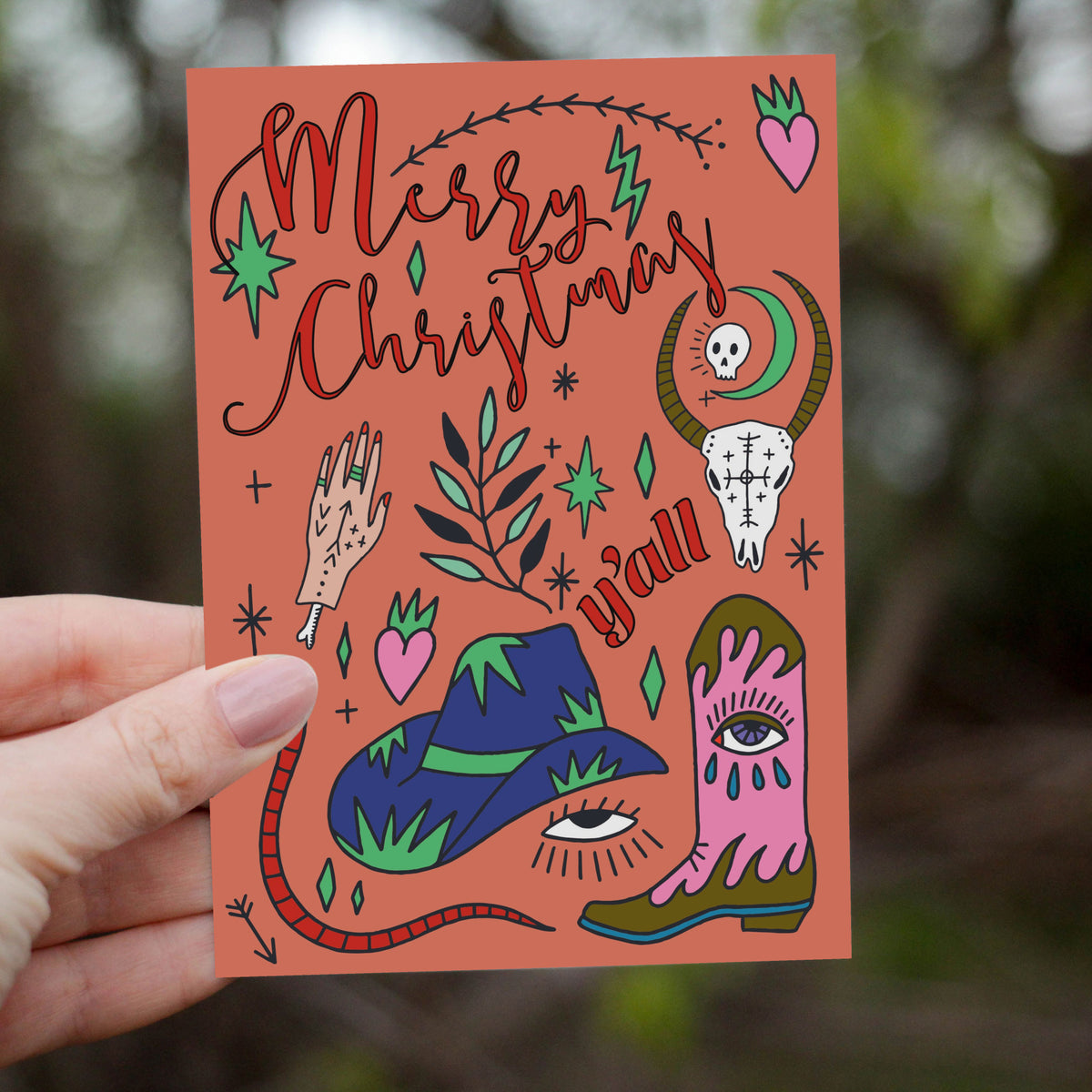 Illustrated Christmas cards with teardrop-eye motifs on boot and hat, animal skull, small skull inside crescent moon.