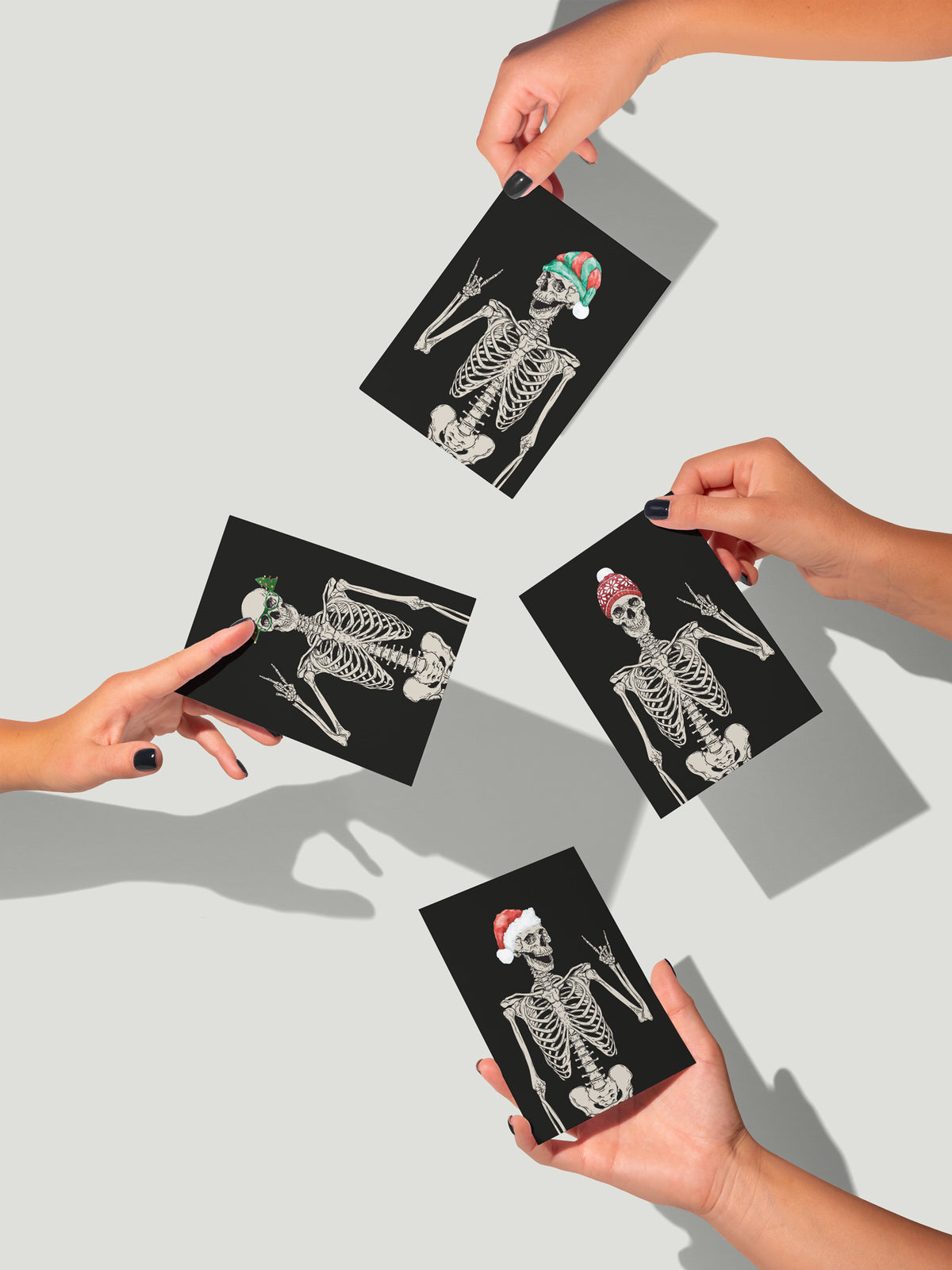Skeleton holiday cards with small full-color hat and glasses accents against solid black card fronts.